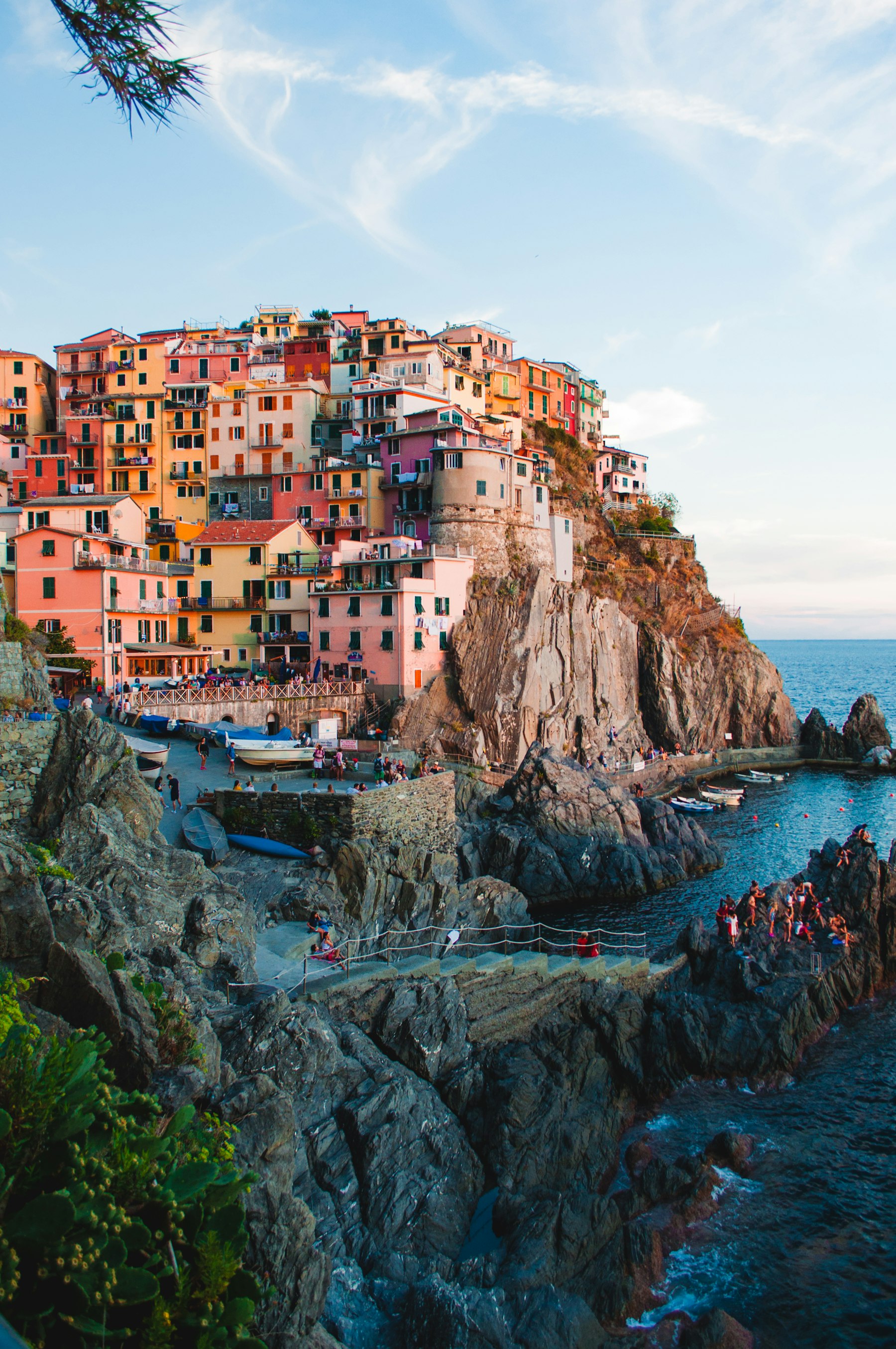 Pastel houses stacked on a cliff above the sea, late afternoon.